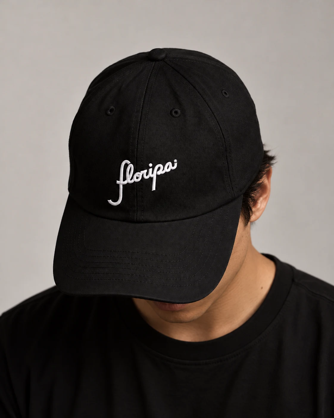 Black cap embroidered with the white Floripa script wordmark