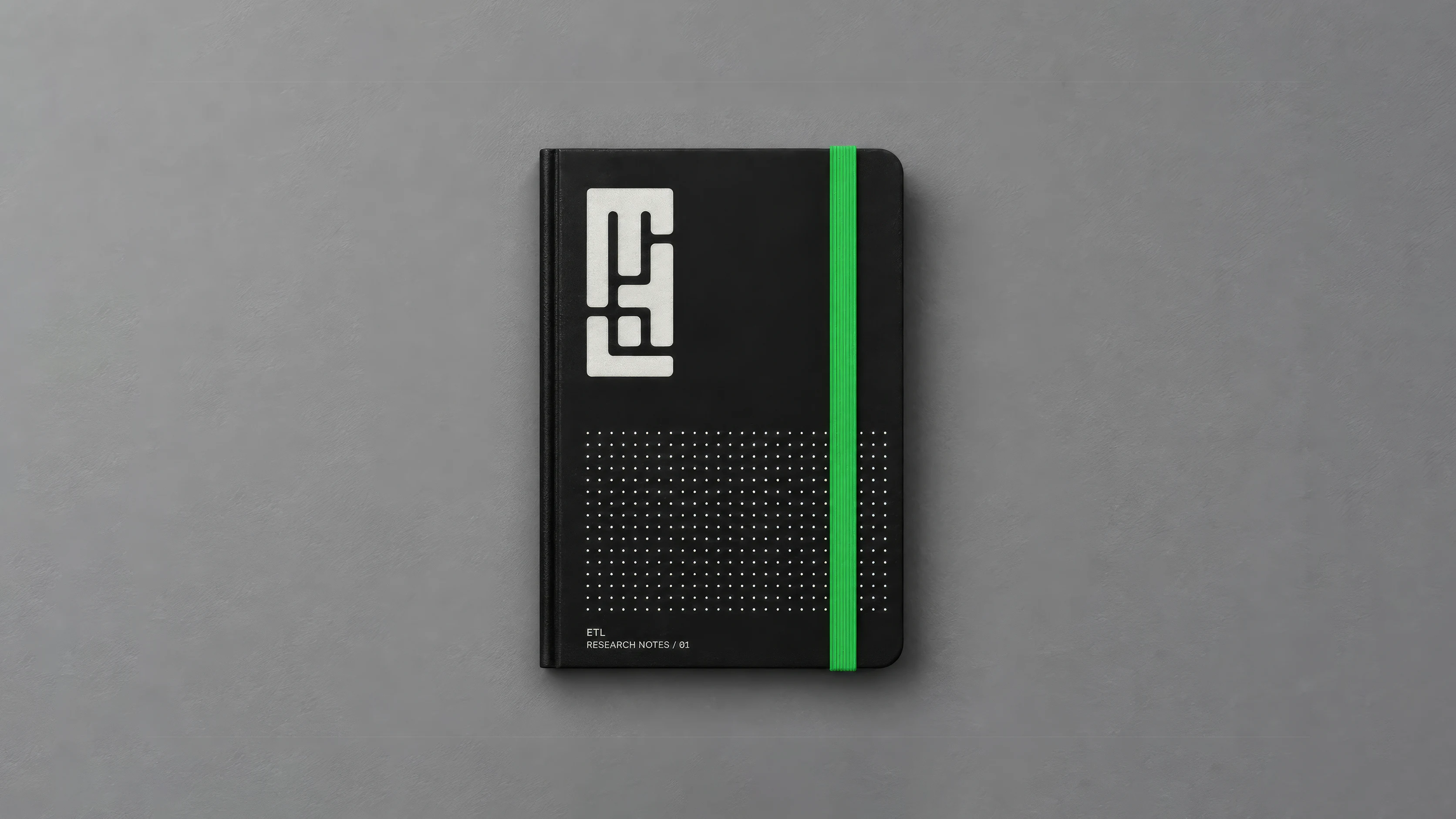 Black ETL notebook with a white monogram and green elastic band